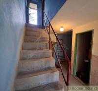 Betontreppen im Inneren der Hütte mit blauen Wänden und einem Metallgeländer.