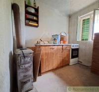 Das Innere der Hütte mit einer einfachen Küchenzeile, einem Ofen und einem offenen Fenster.