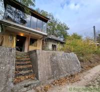 Eine Hütte in Kamenín, umgeben von Grün, mit großen Fenstern und einem Betonvordereingang.