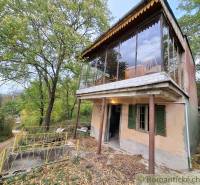 Ein Ferienhaus in Kamenín, umgeben von Grün, mit einer verglasten Terrasse und einer Zufahrtsstraße.
