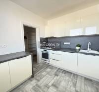 Küche in einer 2-Zimmer-Wohnung mit weißen Möbeln und einem Boden in Holzoptik.