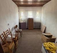 Einfaches Zimmer mit Kartons und Holzstühlen in einem Einfamilienhaus.