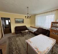 Wohnzimmer in einem Einfamilienhaus mit Sofa, Bücherregal und Tisch mit Tischdecke.