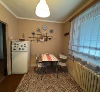 Küche in einem Einfamilienhaus mit Kühlschrank, Tisch und Dekorationsgegenständen an der Wand.