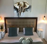 Schlafzimmer mit stilvoller Beleuchtung und einem Bild eines Elefanten in einer 2-Zimmer-Wohnung.