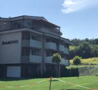 Ein 2-Zimmer-Wohnung in Podhájska, umgeben von Grünflächen und einem wolkenlosen Himmel.