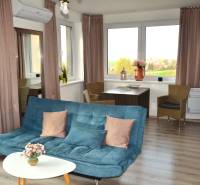 Wohnzimmer mit Sofa, Tisch, Pflanzen und Holzboden in einer Zweizimmerwohnung.