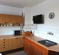 Küche in einem Einfamilienhaus mit einer Holzküchenzeile, einer Mikrowelle und einem Fernseher an der Wand.