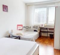 Schlafzimmer in einer 4-Zimmer-Wohnung mit Bett, Tisch und Boden in Holzoptik.