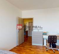 Ein Zimmer in einer 4-Zimmer-Wohnung mit einem Boden in Holzoptik, einem Schreibtisch und einer Kommode.