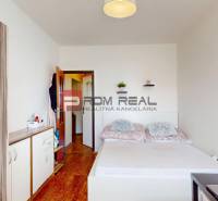 Schlafzimmer in einer 4-Zimmer-Wohnung mit Holzboden, Bett und Schrank.