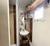 Kompaktes Badezimmer mit Holzregal und Duschkabine in einem Einfamilienhaus.