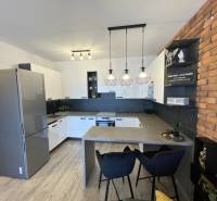 Küche in einer 2-Zimmer-Wohnung mit Holzboden und Backsteinverkleidung an der Wand.