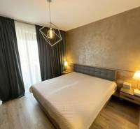 Schlafzimmer mit Bett, Holzboden und Vorhängen in einer Zweizimmerwohnung.