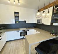 Küche in einer 2-Zimmer-Wohnung mit weißen Schränken und einem Boden in Holzoptik.