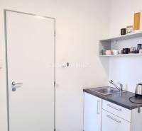 Kleine Büroküche mit Spüle, Regal und Wasserkocher.