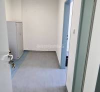 Innenraum eines Büros mit weißen Wänden, abschließbarem Schrank und Boden in Holzoptik.