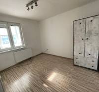 Ein Zimmer in einer 3-Zimmer-Wohnung mit einem Boden in Holzoptik und einfacher Einrichtung.