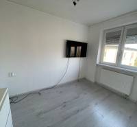 Ein Zimmer in einer 3-Zimmer-Wohnung mit einem Fernseher, einem Boden in Holzoptik und weißen Wänden.