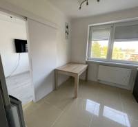 Izba v 3-izbovom byte s dlažbou, oknom a stolom.