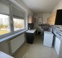 Eine Küche mit einem großen Fenster, einem Heizkörper und einer Küchenzeile in einer 3-Zimmer-Wohnung.