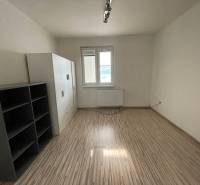 Ein Zimmer in einer 3-Zimmer-Wohnung mit einem Boden in Holzoptik und einfacher Einrichtung.