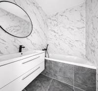 Badezimmer mit Marmorfliesen, ovalem Spiegel und modernem Waschbecken in einer 3-Zimmer-Wohnung.