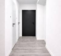 Ein Flur mit hellen Wänden und einem Boden in Holzoptik in einer 3-Zimmer-Wohnung.