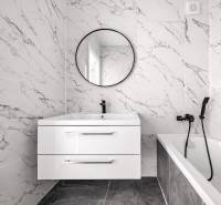 Badezimmer in einer 3-Zimmer-Wohnung mit Marmorfliesen, Waschbecken und Spiegel.