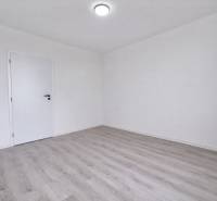 Ein leerer Raum in einer 3-Zimmer-Wohnung mit Holzboden und weißen Wänden.