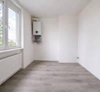 Ein Zimmer mit weißen Wänden und einem Holzboden in einer 3-Zimmer-Wohnung.