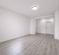 Ein geräumiges Zimmer in einer 3-Zimmer-Wohnung mit einem Boden in Holzoptik und weißen Wänden.