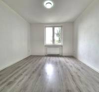 Ein leerer Raum mit Holzboden und weißen Wänden in einer 3-Zimmer-Wohnung.