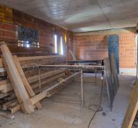 Baustelle einer 3-Zimmer-Wohnung mit unvollendeten Ziegelwänden und Holzbalken.