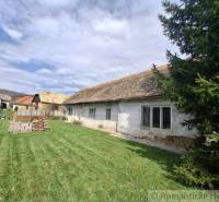 Ein Einfamilienhaus in Ozdín mit ursprünglichem Aussehen und einem grasbewachsenen Hof, umgeben von Bäumen.