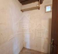 Ein kleines Zimmer mit Betonboden in einem Einfamilienhaus, Holzdecke, einfache Wände.