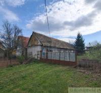 Ein Einfamilienhaus in Ozdín, umgeben von einem Garten und Bäumen, unter blauem Himmel.