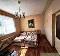 Schlafzimmer im Einfamilienhaus mit Bett, Kronleuchter, Bild und Boden mit Holzdekor.