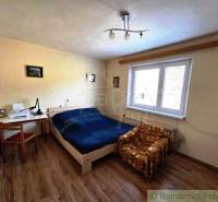 Schlafzimmer mit Bett, Tisch und Stuhl in einem Einfamilienhaus. Boden mit Holzdekor.