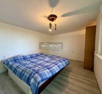 Ein ruhiges Schlafzimmer mit einem einfachen Bett und einem Boden in Holzoptik.