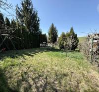 Die Gärten in Rimavská Sobota sind von Nadelbäumen und gepflegtem Rasen unter blauem Himmel umgeben.