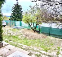 Ein Einfamilienhaus in Bratislava-Záhorská Bystrica, Podkerepušky mit einem grasbewachsenen Hof und Bäumen.