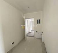 Der Flur in der 2-Zimmer-Wohnung mit weißen Wänden, Türen und einem Boden im Rohzustand.