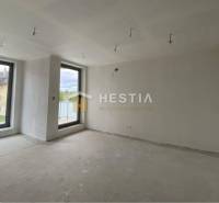 Ein geräumiges Zimmer mit zwei großen Fenstern in einer 2-Zimmer-Wohnung.