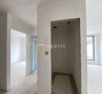 Innenraum einer unvollendeten 2-Zimmer-Wohnung mit verputzten Wänden und einem großen Fenster.