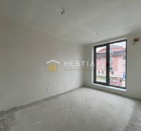Ein Zimmer in einer 2-Zimmer-Wohnung mit rohem Boden und einem großen Fenster mit Blick auf die Straße.