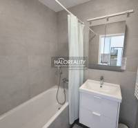 Badezimmer mit Badewanne, Waschbecken und Spiegel in einer 2-Zimmer-Wohnung.