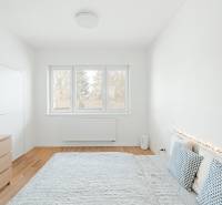 Helles Schlafzimmer in einer Vierzimmerwohnung mit Holzboden und dekorativen Kissen.