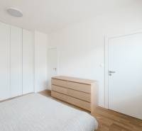 Schlafzimmer in einer 4-Zimmer-Wohnung mit weißen Wänden und einem Boden in Holzoptik.