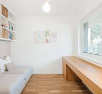 Helles Zimmer mit Holzboden, Sofa und großen Fenstern.